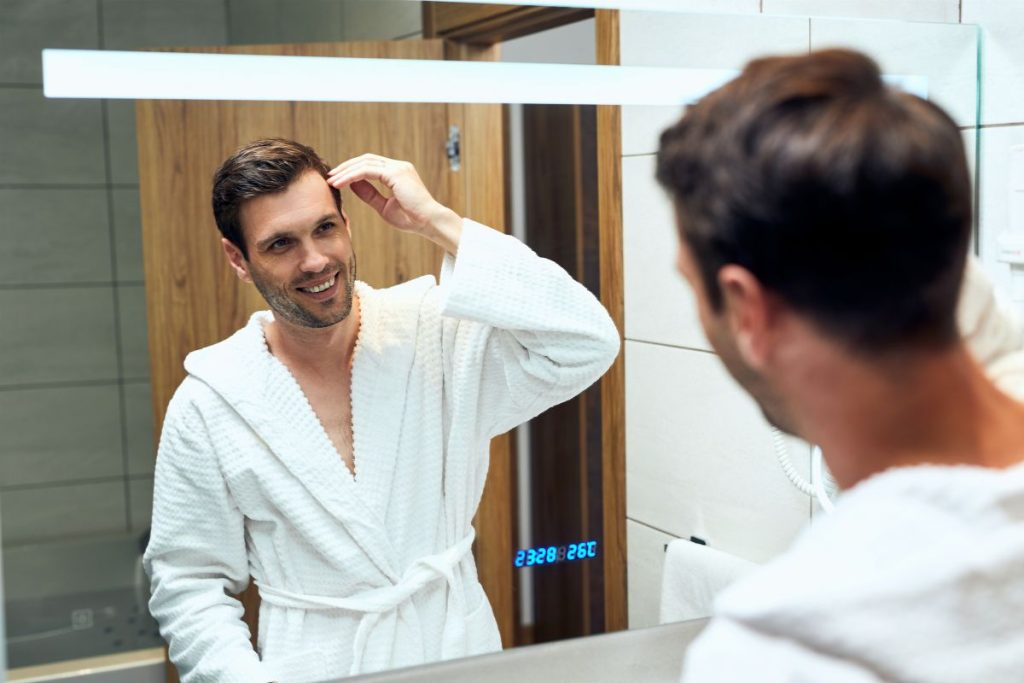 Hombre en un espejo, mirando su cabello fortalecido gracias a Vitybell