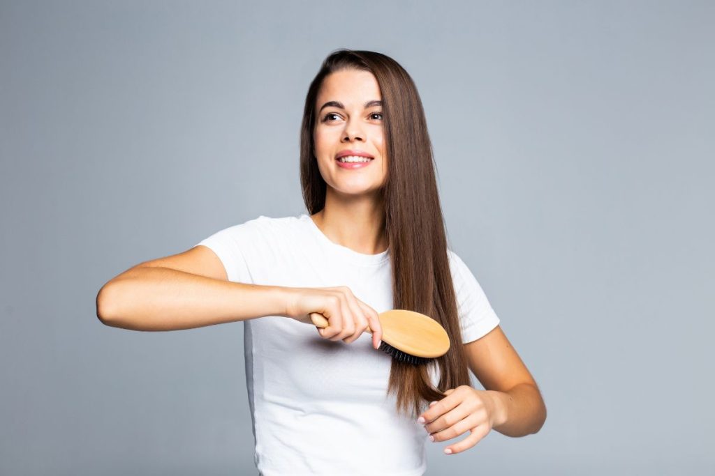 Mujer feliz gracias a las vitaminas y suplementos que ayudan a fortalecer el cabello